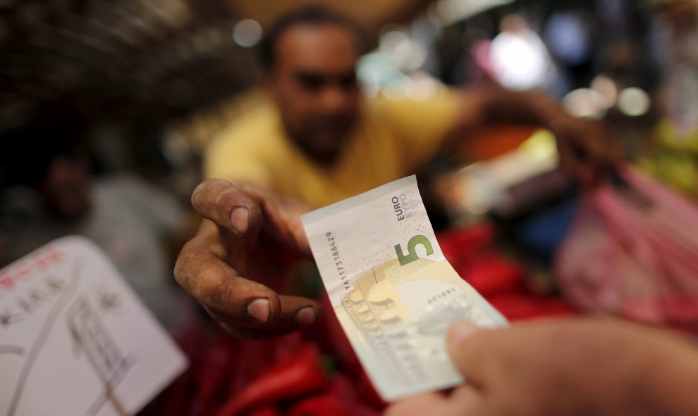 Un vendedor coge un billete de cinco euros de un cliente en el mercado centrasl de Atenas, Grecia. REUTERS/Christian Hartmann