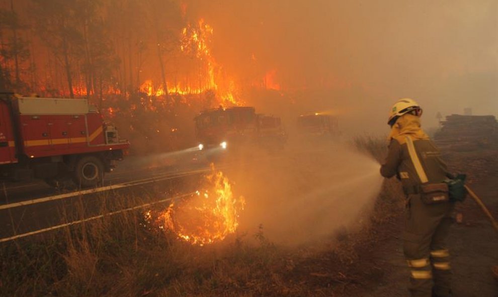 Un bombero muy cercano al fuego intenta apagarlo con una manguera en Santiago de Compostela/EFE