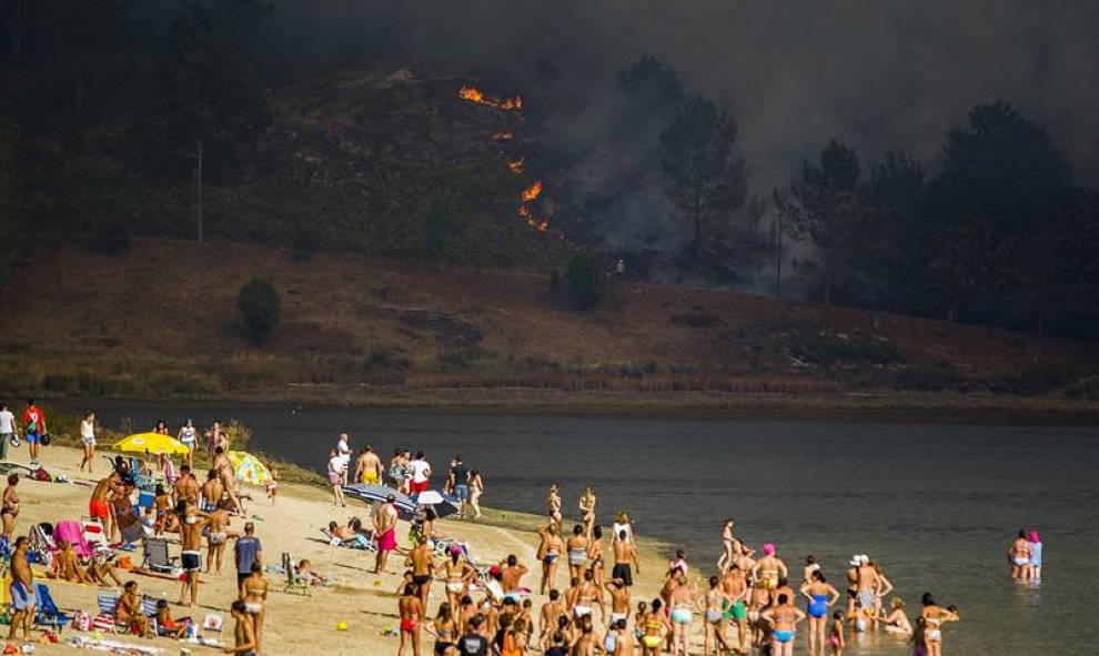 El incendio de Soutomaior ha llegado a la playa fluvial del río Verdugo ante la atenta mirada de sus vecinos, que disfrutaban de un baño/EFE