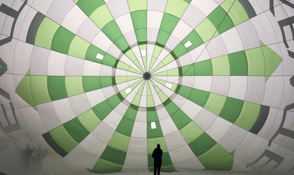 Un hombre ajusta un globo mientras se hincha en la Fiesta Internacional de Globos de Bristol, Inglaterra. REUTERS/Neil Hall