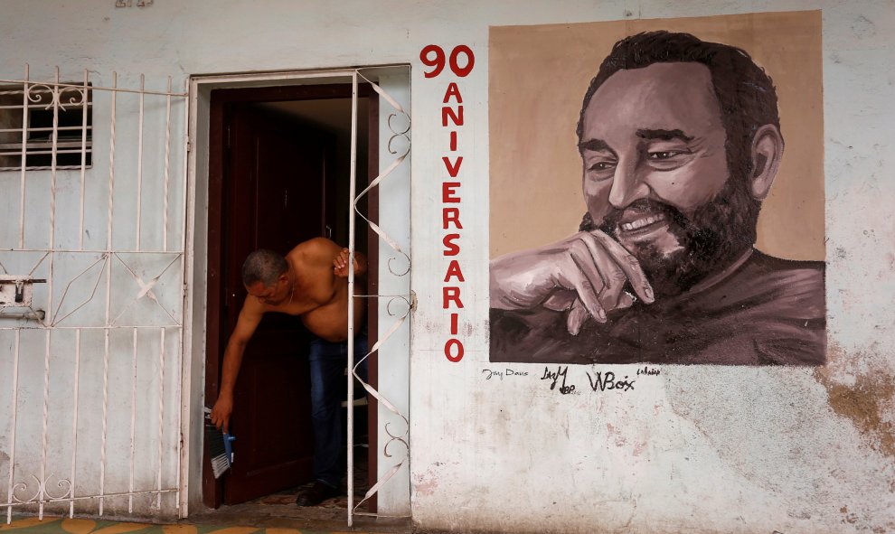 Un hombre en la puerta de su vivienda en La Habana, en cuya fachada tiene pintado un retrato de Fidel Castro. REUTERS/Stringer