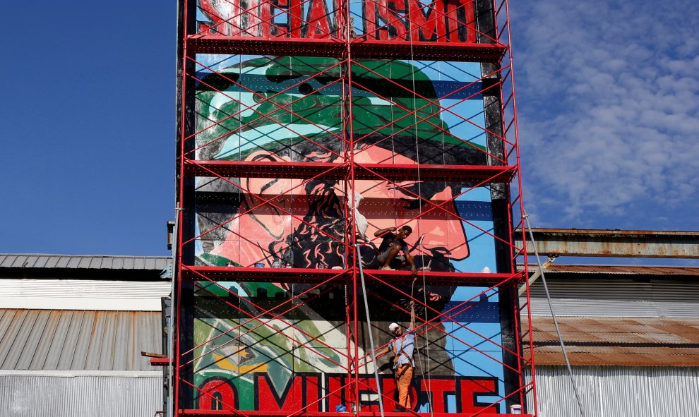 Un hombre pintanto un cartel con el retrato de Fidel Castro con el rótulo 'Socialismo o Muerte', en La Habana. REUTERS/Stringer