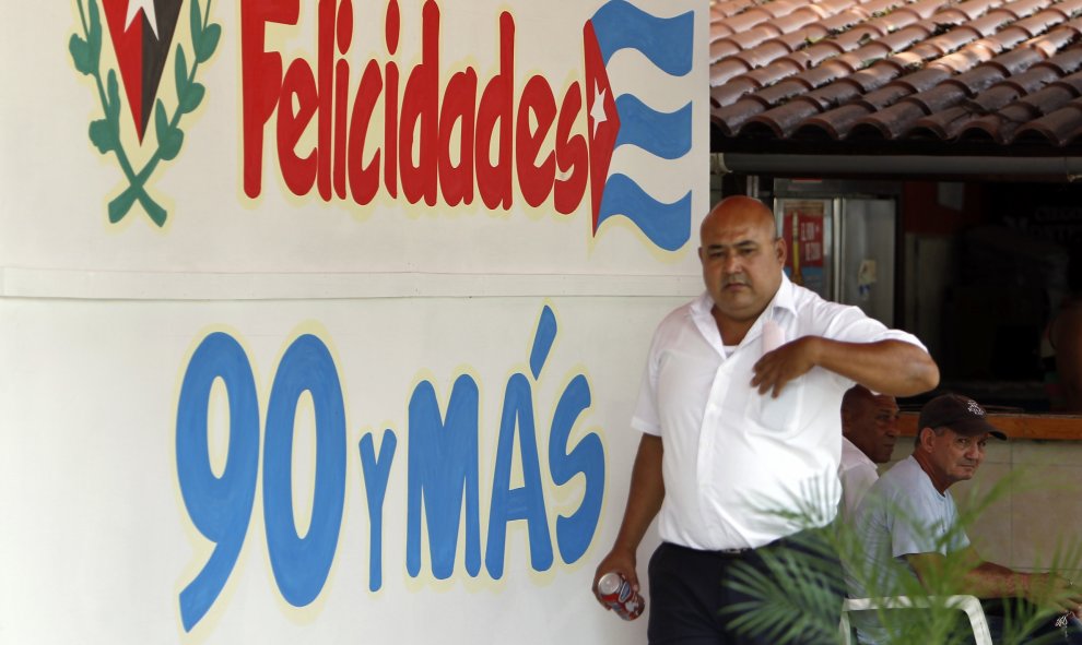 Un hombre pasa en La Habana (Cuba) junto a un mensaje alusivo al cumpleaños 90 del líder de la revolución cubana Fidel Castro. EFE/Ernesto Mastrascusa