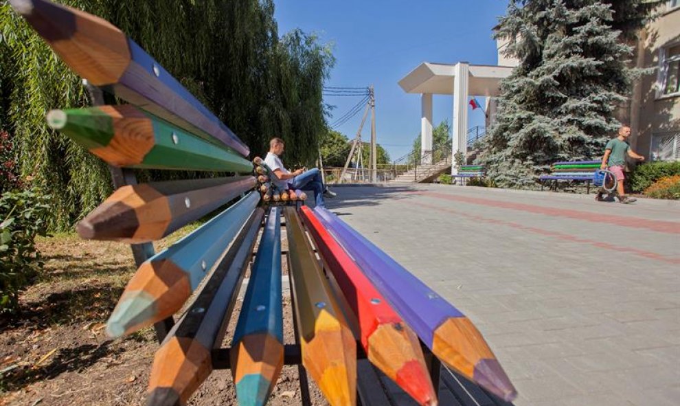 Un hombre sienta en un banquillo hecho de lápices de color cerca de un colegio en Ialoveni, a 15 kilómetros de Chisináu, Moldavia. Se celebra el Día Nacional del Idioma Moldavo desde 1989. EFE/Dumitru Doru