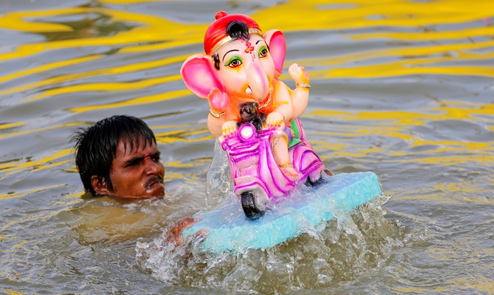 Un hombre se sumerge junto a un ídolo del dios hindú Ganesh, el dios de la prosperidad, en un estanque en el segundo día del festival de Ganesh Chaturthi en Ahmedabad, India. REUTERS / Dave Amit