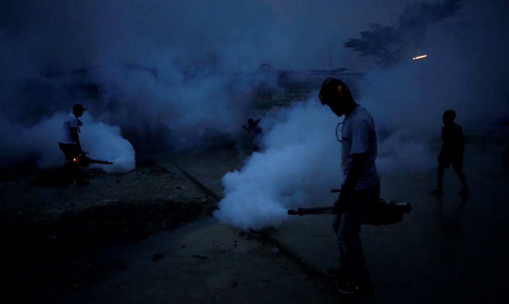Trabajadores del Ministerio de Salud Pública y Población fumigan la calle para evitar la reproducción de los mosquitos y prevenir enfermedades como la malaria, el dengue y el Zika, durante una campaña de fumigación en Port-au -Prince, Haití. REUTERS/Andre