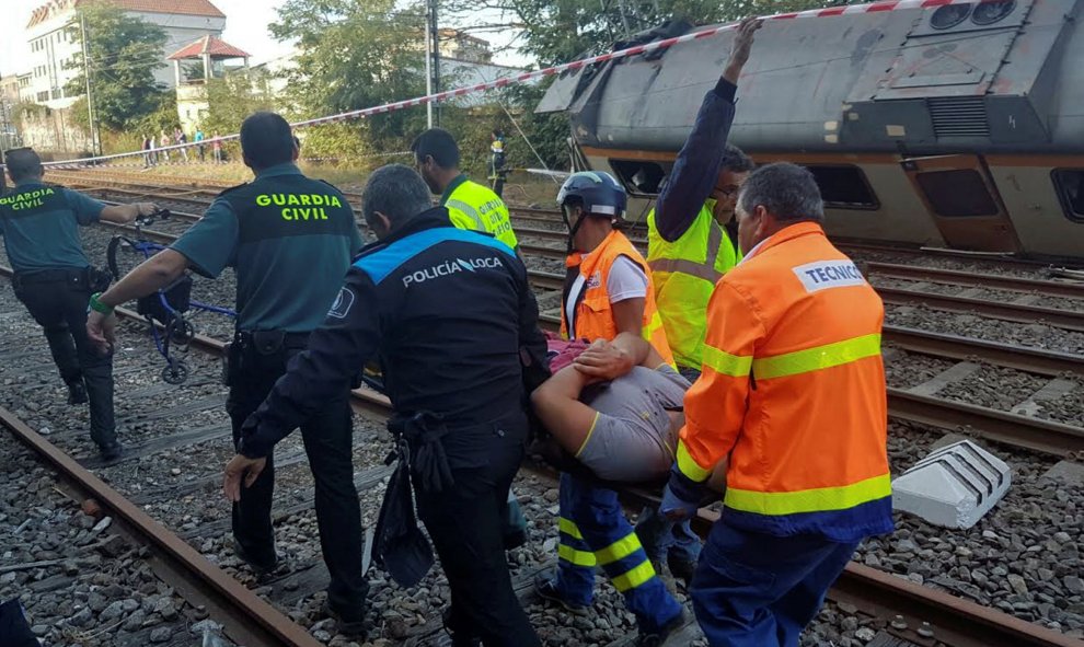 Policías y trabajadores trasladana  un herido tras el accidente del tren que ha descarrilado en O Porriño, Galicia. REUTERS/Vigoalminuto.com