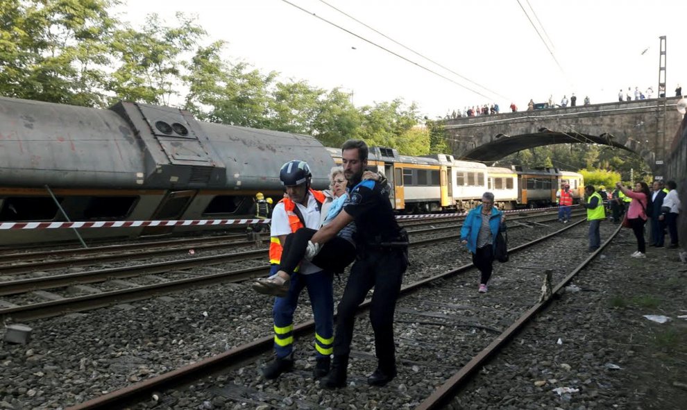 Policías y trabajadores trasladan a un herido tras el accidente en el que ha descarrilado un tren en O Porriño, Galicia. REUTERS/Vigoalminuto.com