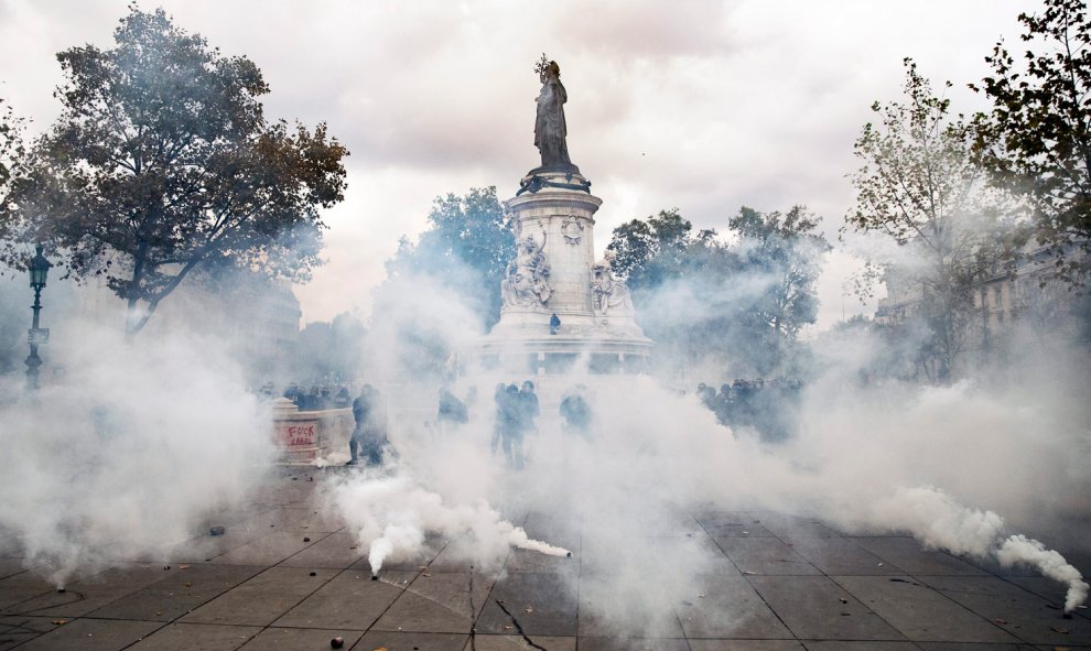 Vista de varios policías detrás de los botes de gas lacrimógenos empleados contra los manifestantes durante una manifestación contra la nueva reforma laboral en París.- EFE/Etienne Laurent