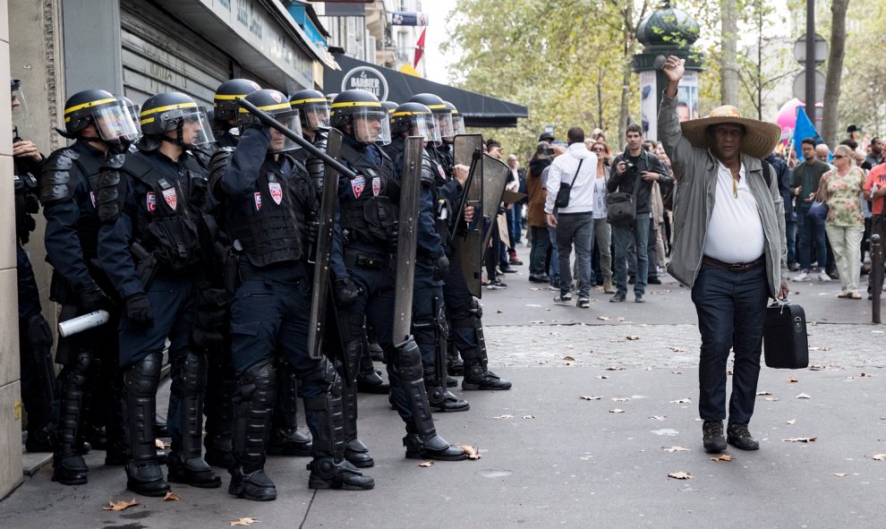 Un peatón levanta el puño a su paso delante de los policías durante una manifestación contra la nueva reforma laboral en París.- EFE/Etienne Laurent