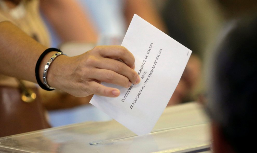 Una  mujer deposita su voto en la urna en un colegio electoral en Vigo. REUTERS/Miguel Vidal