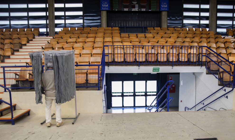 Un hombre elige la papeleta el colegio electoral habiltado en el polideportivo Mendizorrotza de Vitoria.EFE/David Aguilar