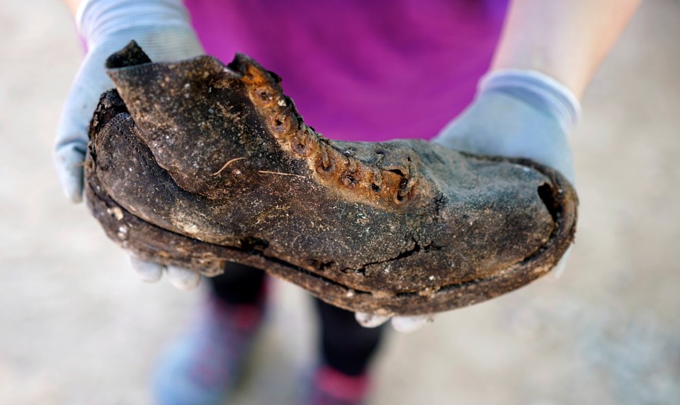 Un miembro de la Asociación por la Recuperación de la Memoria Histórica de Valladolid muestra el zapato de uno de los represaliados por el franquismo exhumados de una fosa junto al cementerio de El Carmen, en Valladolid.- REUTERS / JUAN MEDINA
