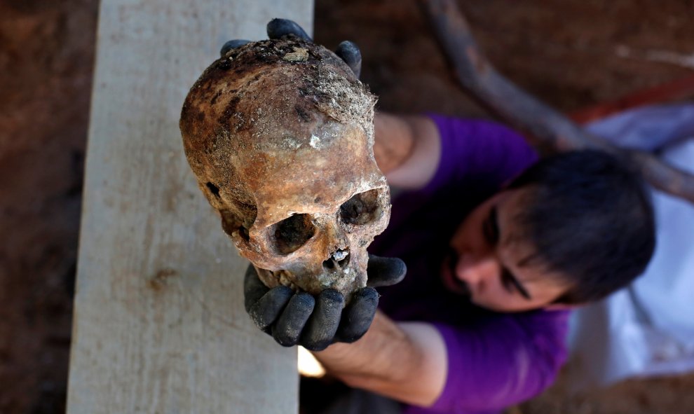 Un arqueólogo de la ARMH-Valladolid sostiene el cráneo de un asesinado por el bando franquista durante la Guerra Civil, en Valladolid.- REUTERS / JUAN MEDINA