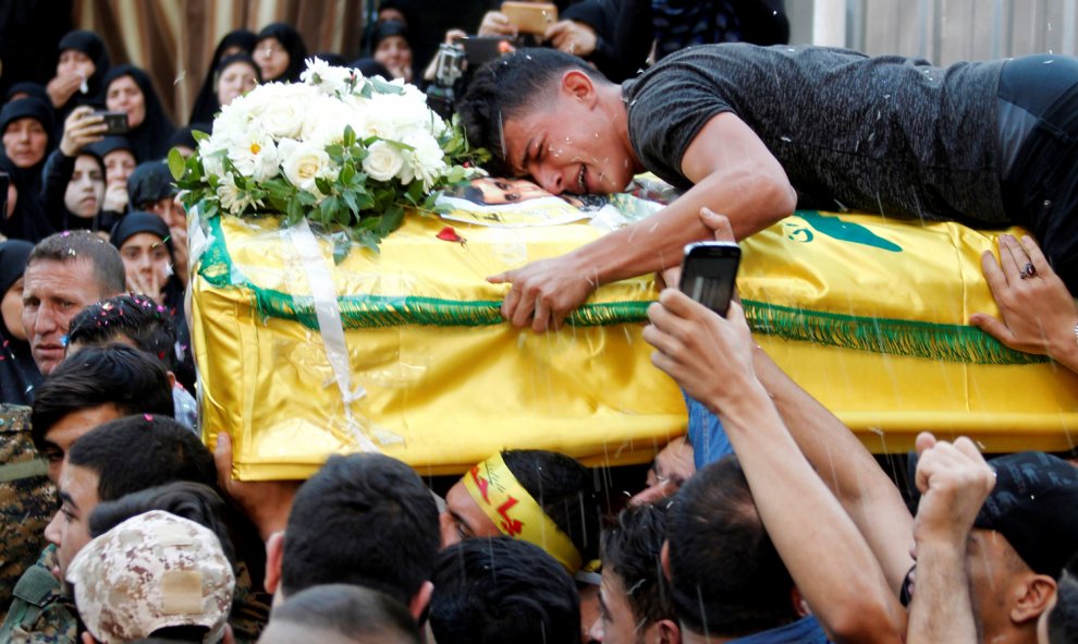 Un hombre llora sobre el ataúd de un soldado de Hezbollah fallecido en Alepo, durante su funeral en Beirut. /REUTERS