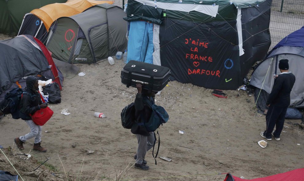 Un grupo de refugiados, junto a una pintada que dice "Amo Francia", en la 'Jungla' de Calais durante la evacuación del campo. REUTERS/Pascal Rossignol