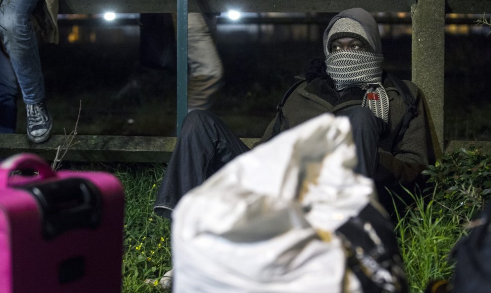 Unos inmigrantes esperando los autobuses que evacúan la 'Jungla' de Calais. EFE/EPA/Etienne Laurent