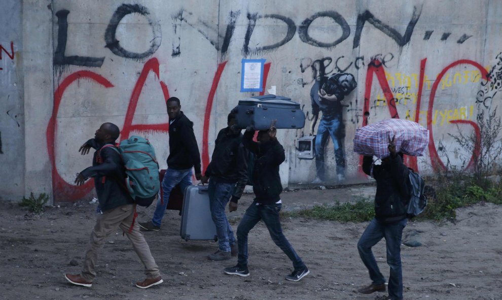 Un grupo de refugiados porta sus pertenencias durante la evacuación de la 'Jungla' de Calais. REUTERS/Pascal Rossignol