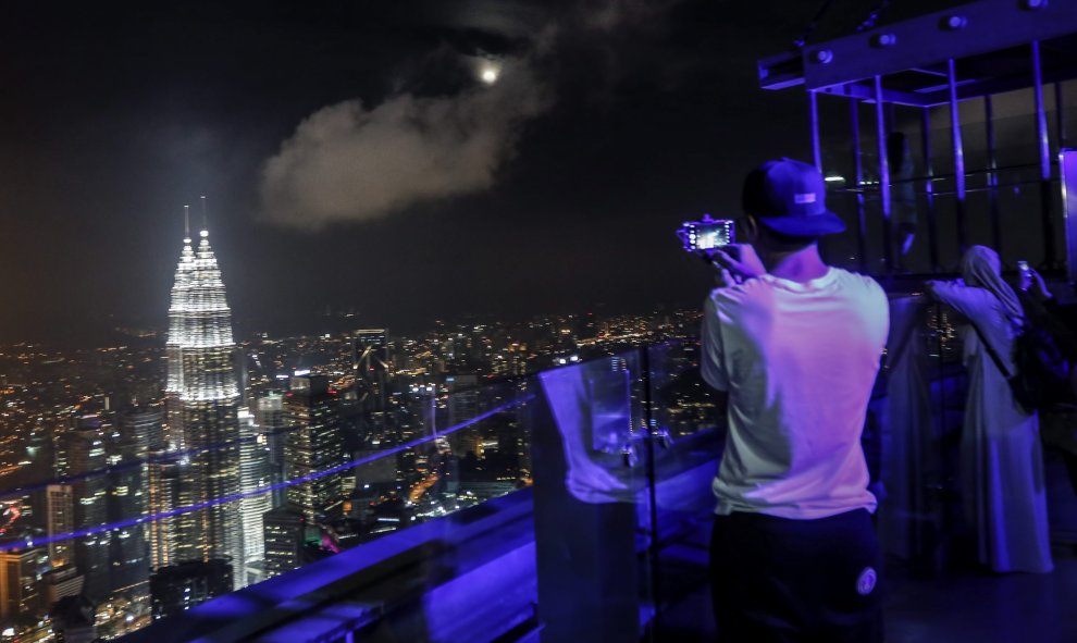 Un turista toma una fotografía de la superluna en la Torre de Kuala Lumpur en Kuala Lumpur (Malasia). EFE/Ahmad Yusni