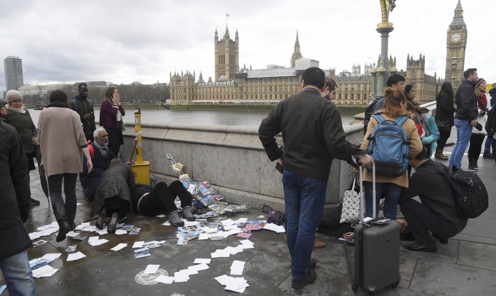 Varias personas atienden a un herido en el puente delante del Parlamento / REUTERS