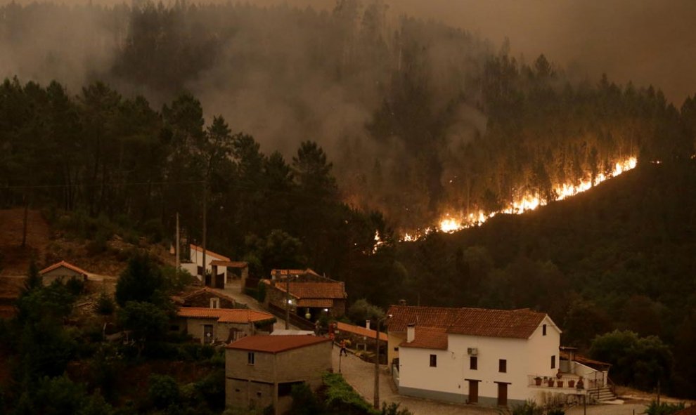 Las llamas cercan el pueblo de Mega Fungueira. | MIGUEL VIDAL (REUTERS)