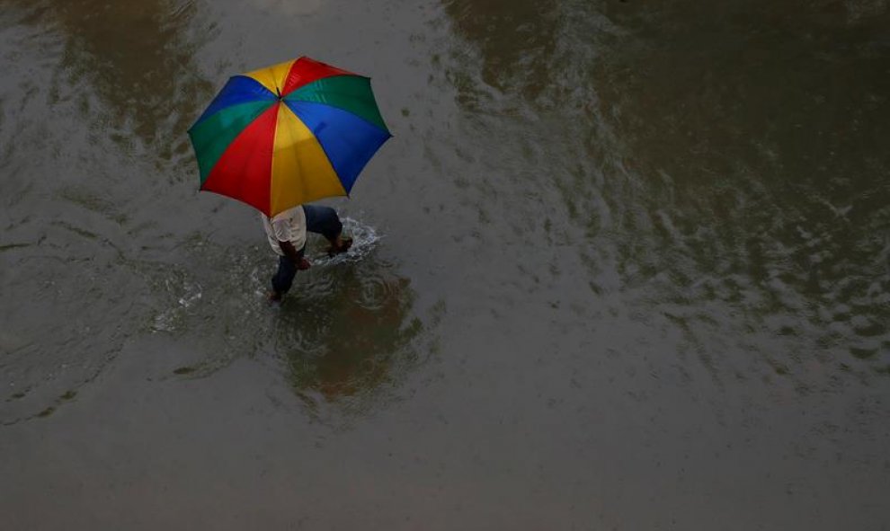 Un hombre con un paraguas camina por una zona inundada en Rajbiraj, distrito de Saptari, Nepal. EFE/EPA/NARENDRA SHRESTHA