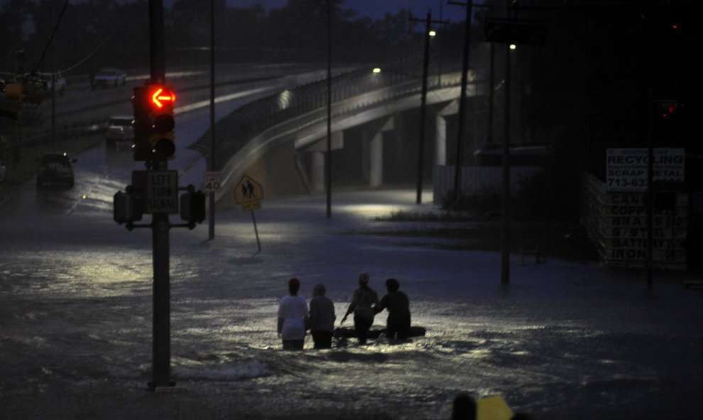 Varias personas caminan entre el agua acumulada tras la inundación provocada por el huracán Harvey en la costa del golfo de Texas, en Houston, EEUU.- REUTERS / Nick Oxford