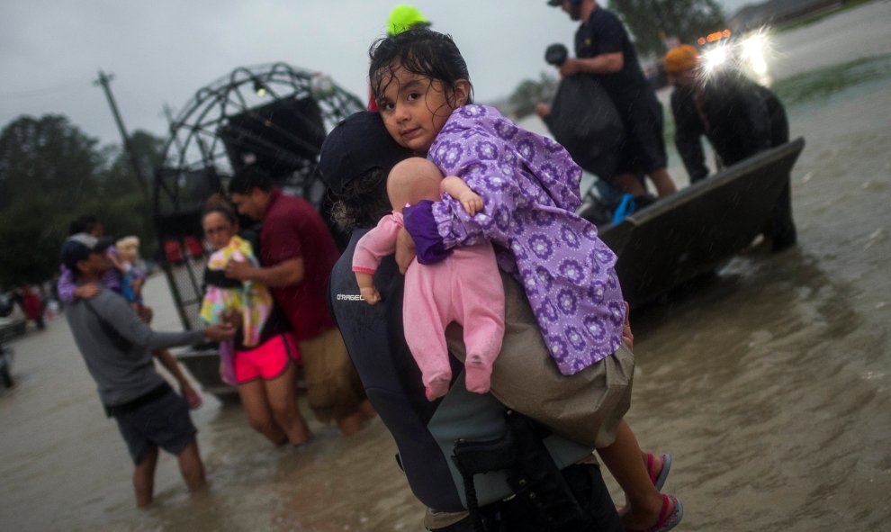 Una mujer sostiene a una niña mientras su familia llega a una zona segura en barco tras las inundaciones causadas por la tormenta tropical Harvey en el este de Houston, Texas(EEUU). REUTERS / Adrees Latif