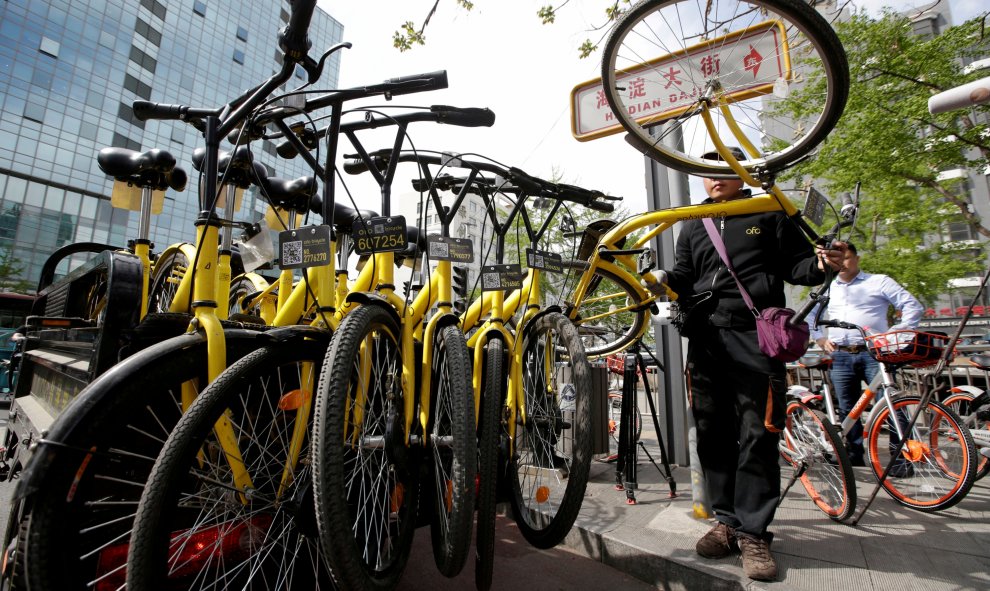 Un miembro del personal de la compañía de bicicletas compartidas Ofo, una de las múltiples de 'startup' que han proliferado rápidamente, reúne sus bicicletas compartidas para usar durante la hora punta de la tarde, en Beijing, China. Al tener GPS incorpor