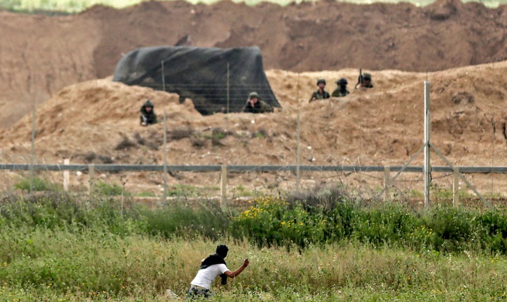 Un palestino arroja piedras a los soldados israelíes al otro lado de la frontera durante los enfrentamientos después de las manifestaciones del Día de la Tierra al este de la ciudad de Gaza.- MAHMUD HAMS / AFP
