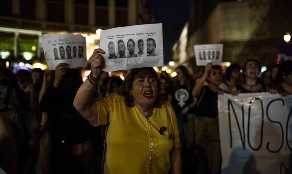 Una mujer muestra las caras de los cinco integrantes de 'la manada' durante la manifestación contra su sentencia condenatoria en Madrid.- JAIRO VARGAS