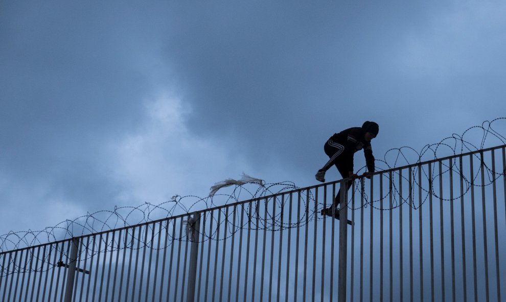 Un menor migrantes salta una valla con cuchillas para acceder al puerto de Ceuta, donde intentará colarse en un ferry para llegar a la península.- PEDRO ARMESTRE / SAVE THE CHILDREN