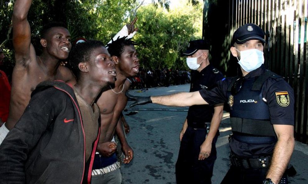 Varios migrantes con dos policias nacionales/EFE