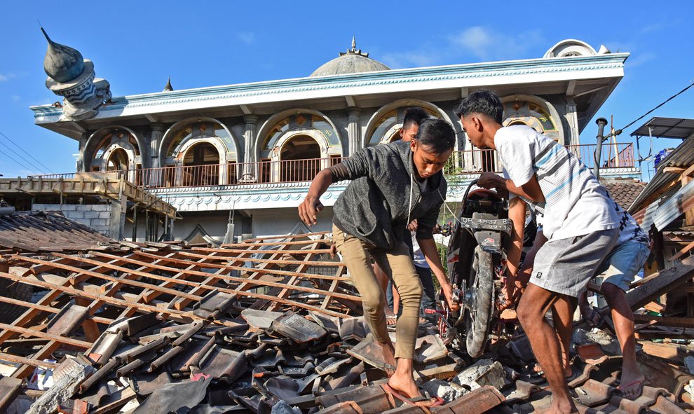 La gente ayuda a recuperar objetos perdidos y a limpiar la zona para facilitar la búsqueda de desaparecidos en Gunungsari, West Lombok, Indonesia. / Reuters