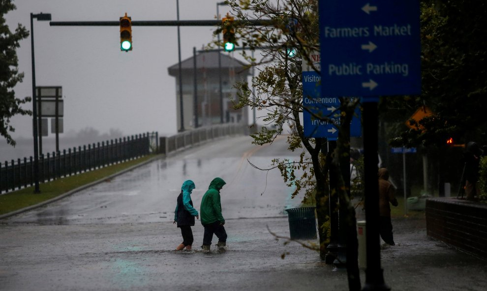 Dos personas en New Bern (Carolina del Norte) cruzan una calle inundada por el agua del río Neuse - REUTERS/Eduardo Munoz