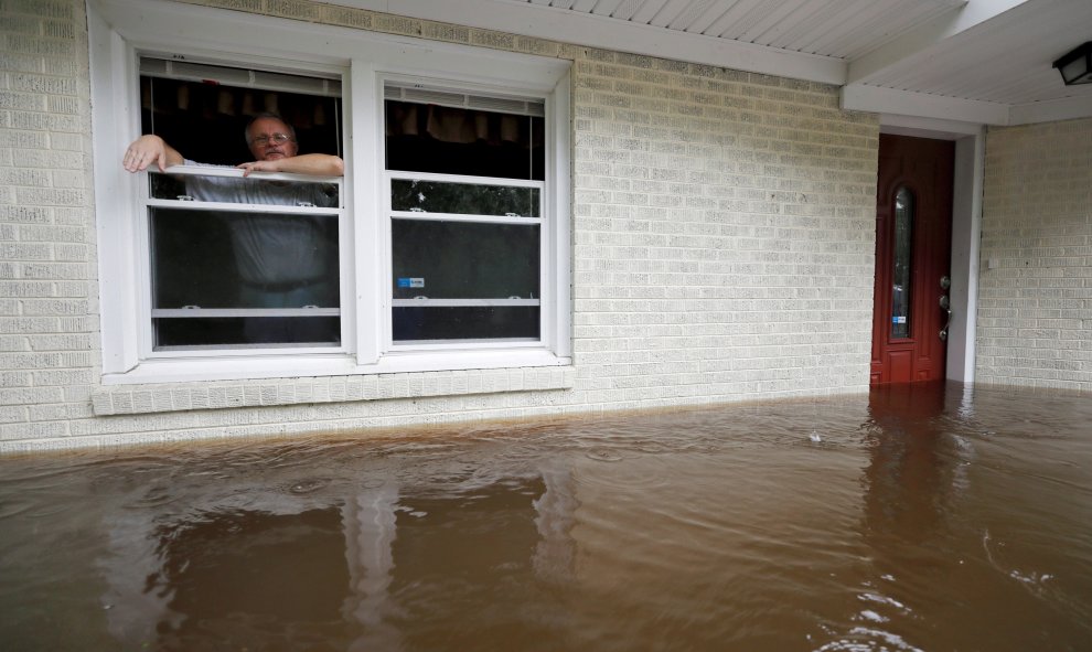 Un hombre espera ser rescatado después de que las precipitaciones hayan rodeado su casa | REUTERS/Jonathan Drake