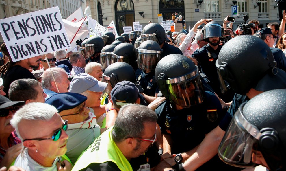 Grupos de pensionistas que se concentraron en el Congreso de los Diputados pidiendo mejoras en sus prestaciones intentan romper el cordón policial intentaba impedir su paso hasta la Cámara. REUTERS/Stringer