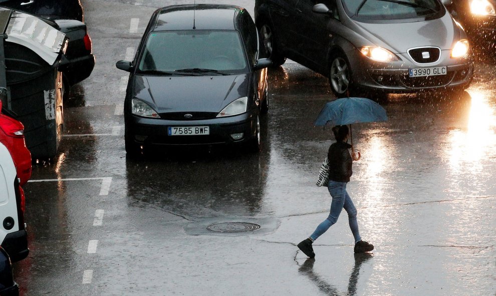 Una persona se protege de la lluvia con un paraguas durante la mañana de este viernes en la que el cielo de la Comunidad Valenciana permanece cubierto con precipitaciones fuertes o muy fuertes, sobre todo en Castellón y Valencia - EFE/Kai Försterling