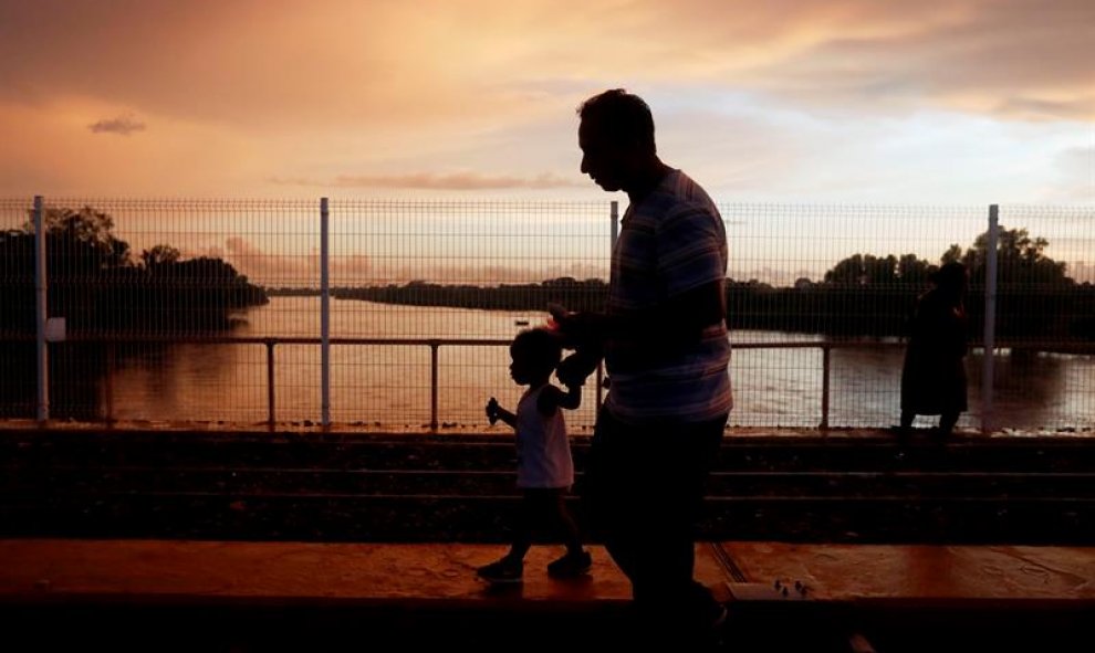 Migrantes hondureños esperan en el puente de la frontera entre Guatemala y México este domingo 21 de octubre de 2018, en Tecún Umán (Guatemala). Las personas, entre ellas niños, siguen esperando para poder ingresar en territorio mexicano y así continuar s