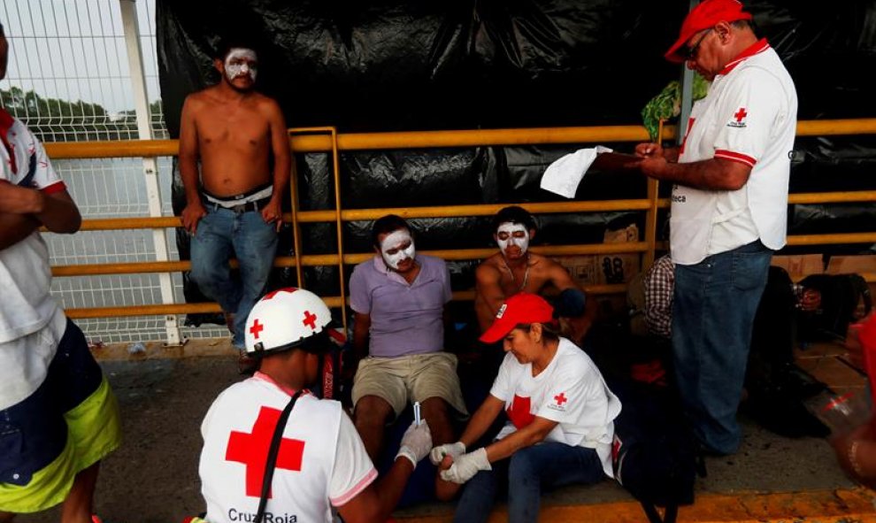 Colaboradores de la Cruz Roja asisten a migrantes hondureños, mientras esperan en el puente de la frontera entre Guatemala y México en Tecún Umán (Guatemala)