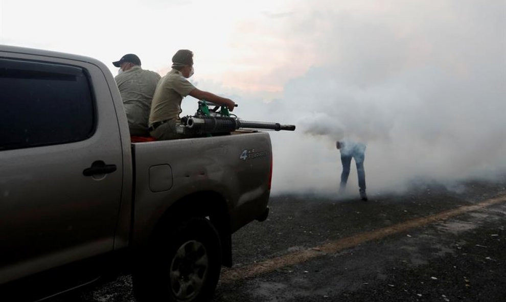 Empleados del ministerio de Salud fumigan contra mosquitos en el puente de la frontera entre Guatemala y México. EFE/ESTEBAN BIBA