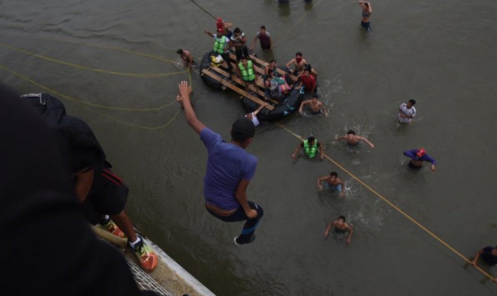 Migrantes hondureños que se encuentran en la frontera de México y Guatemala, se lanzan del puente hacia el río Suchiate para cruzar hacia México. EFE/EDWIN BERCÍAN