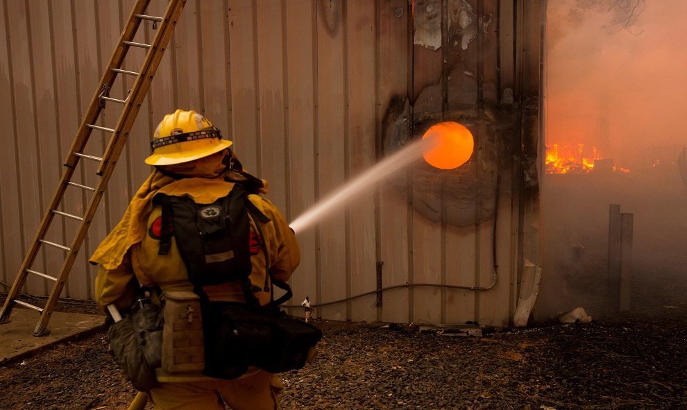 Un bombero apagando un fuego en el interior de una propiedad. EFE/ Peter Dasilva