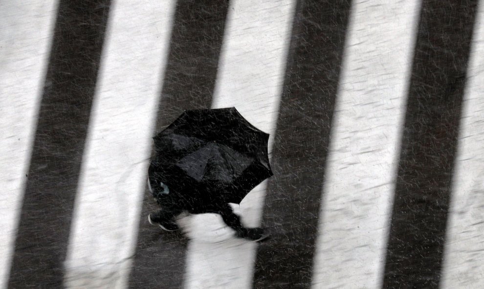 Una persona se protege con un paraguas del fuerte aguacero en València. EFE/Kai Försterling