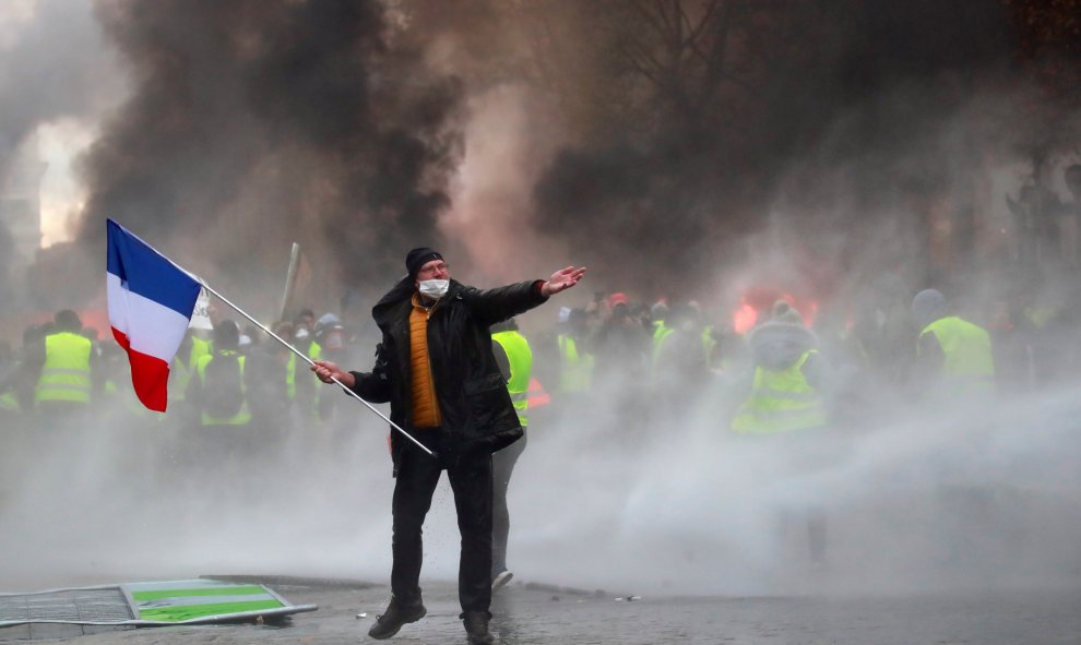Un manifestante sostiene una bandera francesa durante los enfrentamientos entre los "chalecos amarillos" y la policía en París.- REUTERS/Gonzalo Fuentes