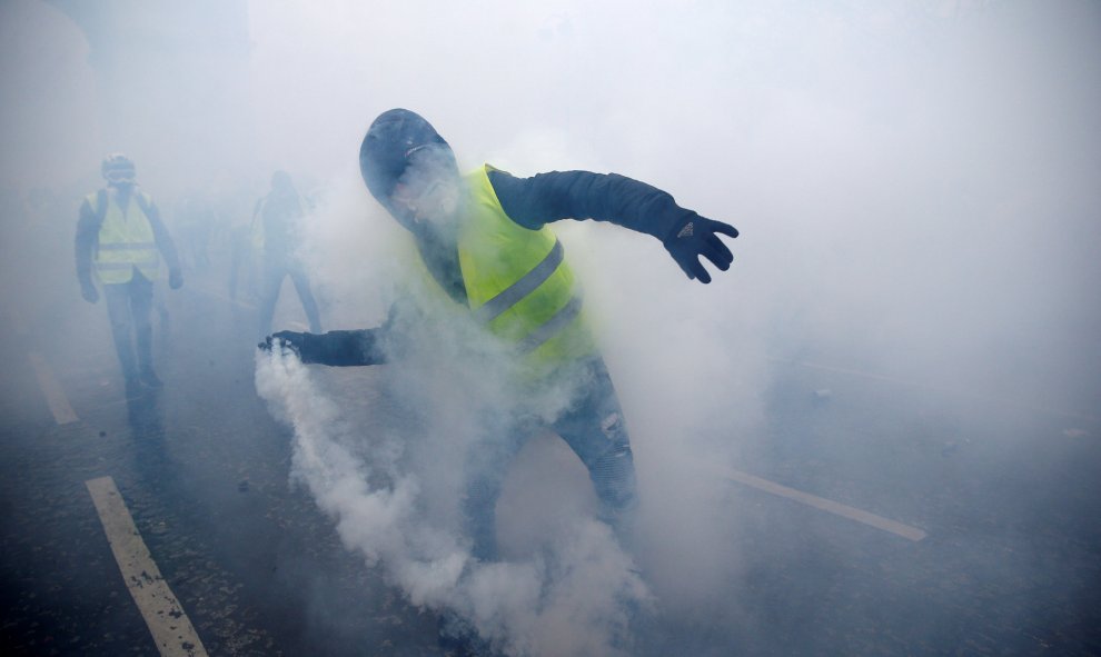 Un hombre, ataviado con un chaleco amarillo, lanza una granada de gas lacrimógeno.- Stephane Mahe/REUTERS