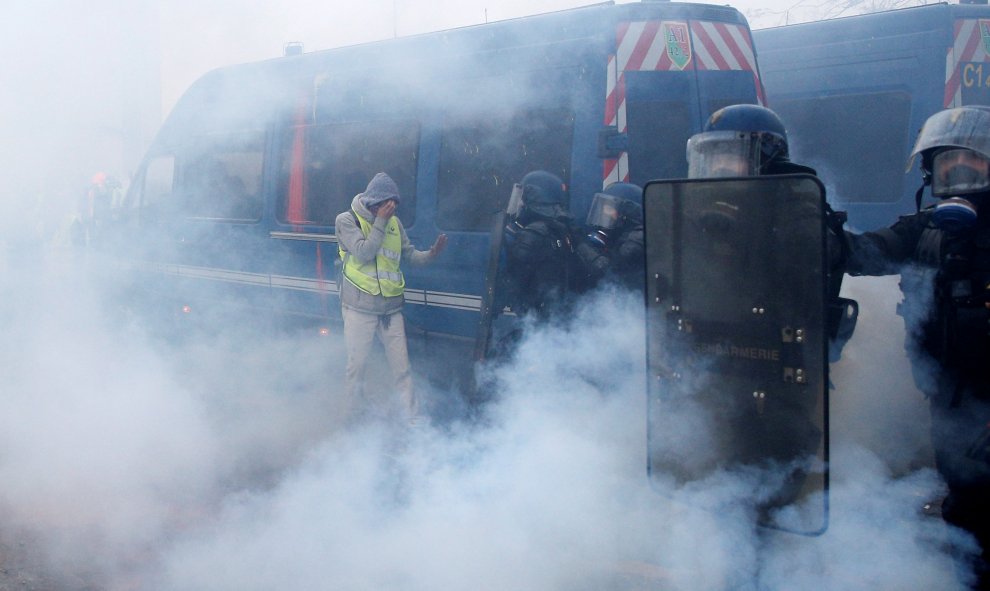 Policías antidisturbios se parapetan tras sus escudos mientras el humo y el gas lacrimógeno les oculta.- Stephane Mahe/REUTERS
