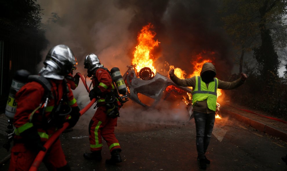 Los bomberos apagan el fuego durante las protestas de los chalecos amarillos en París.- Stephane Mahe/REUTERS