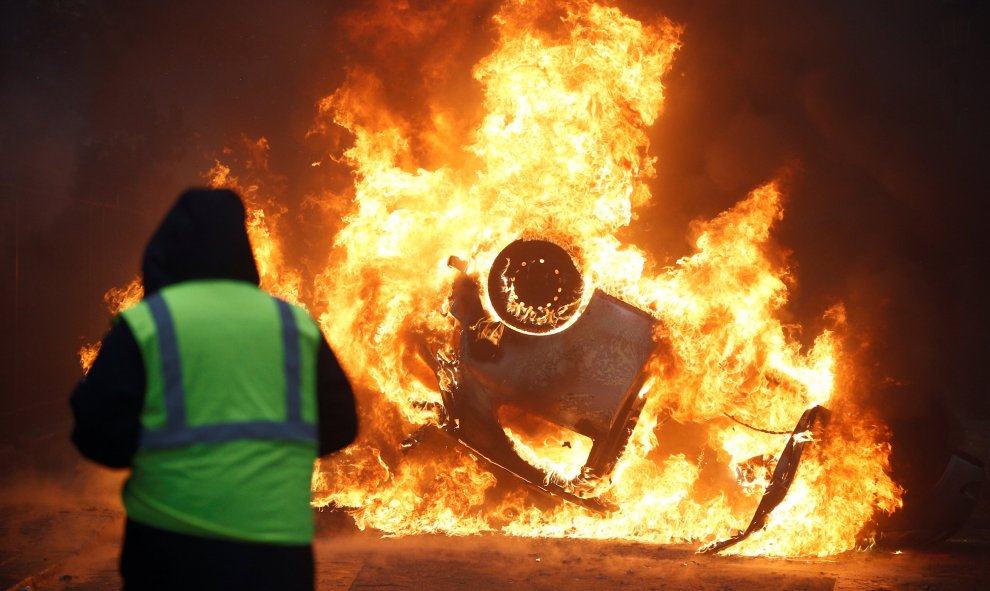 Un hombre ve como arde un coche. Stephane Mahe/REUTERS