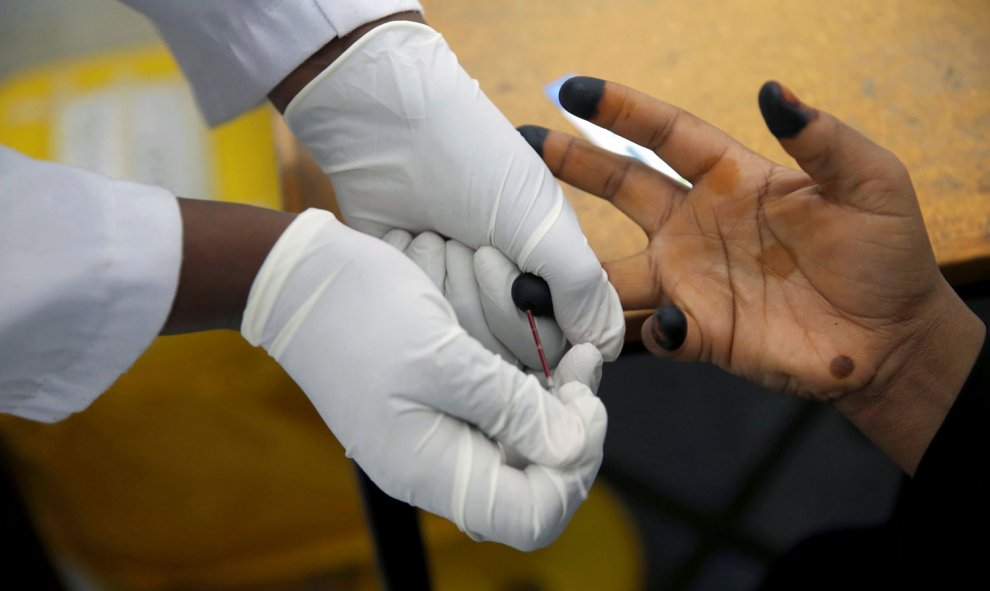 Un consejero sobre la adherencia al VIH extrae la sangre de una mujer para una prueba de VIH en el centro de tratamiento de la OIM en Eastleigh, Nairobi